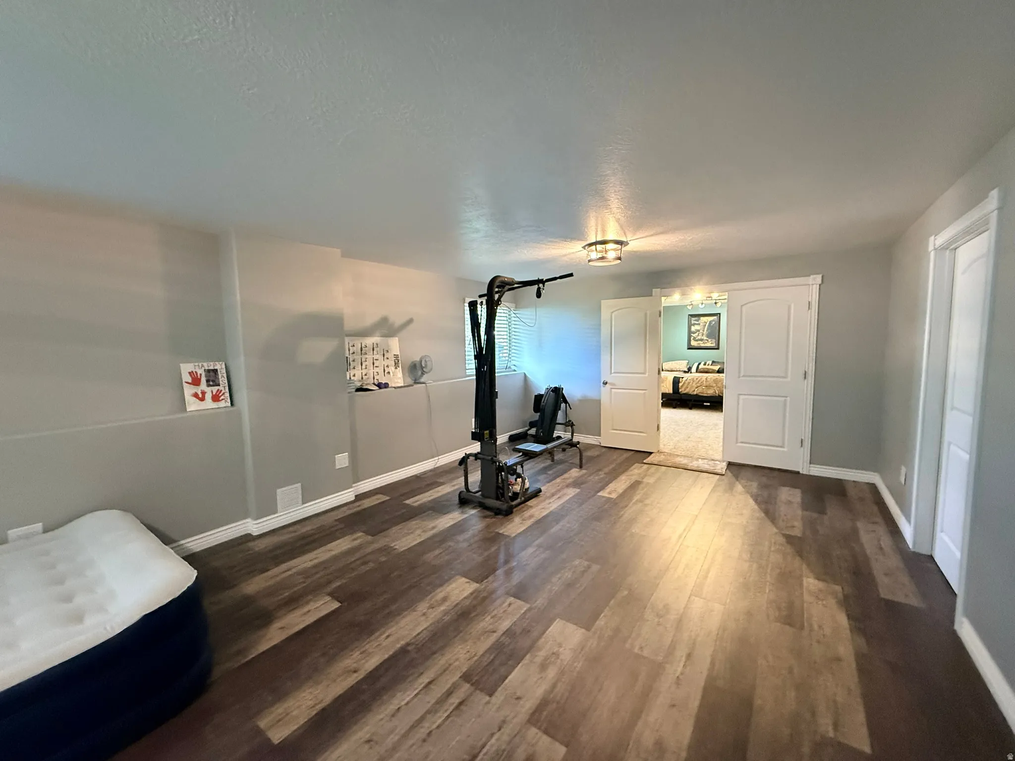 Spacious room featuring wood-finish flooring, light gray walls, and white baseboards