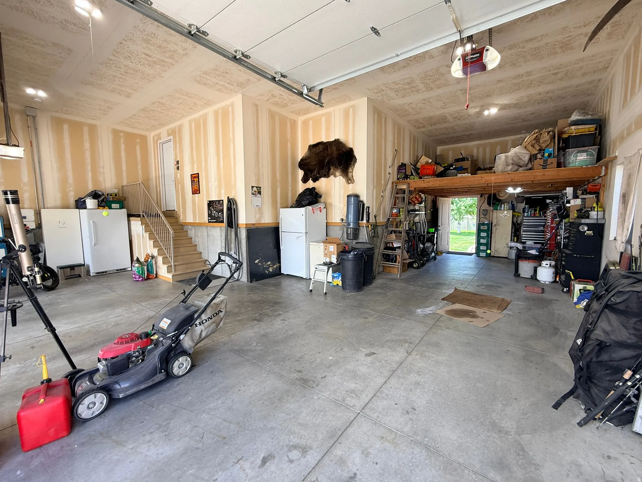 Spacious garage featuring a concrete floor, high ceilings, and a built-in lofted storage area