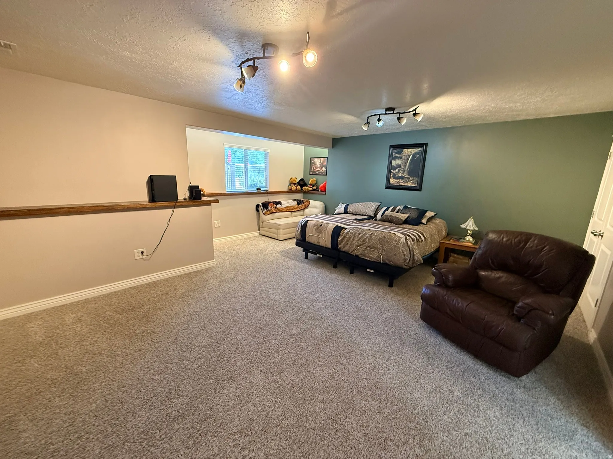 Spacious room featuring neutral carpet flooring and a partial divider wall with a wood-finish top
