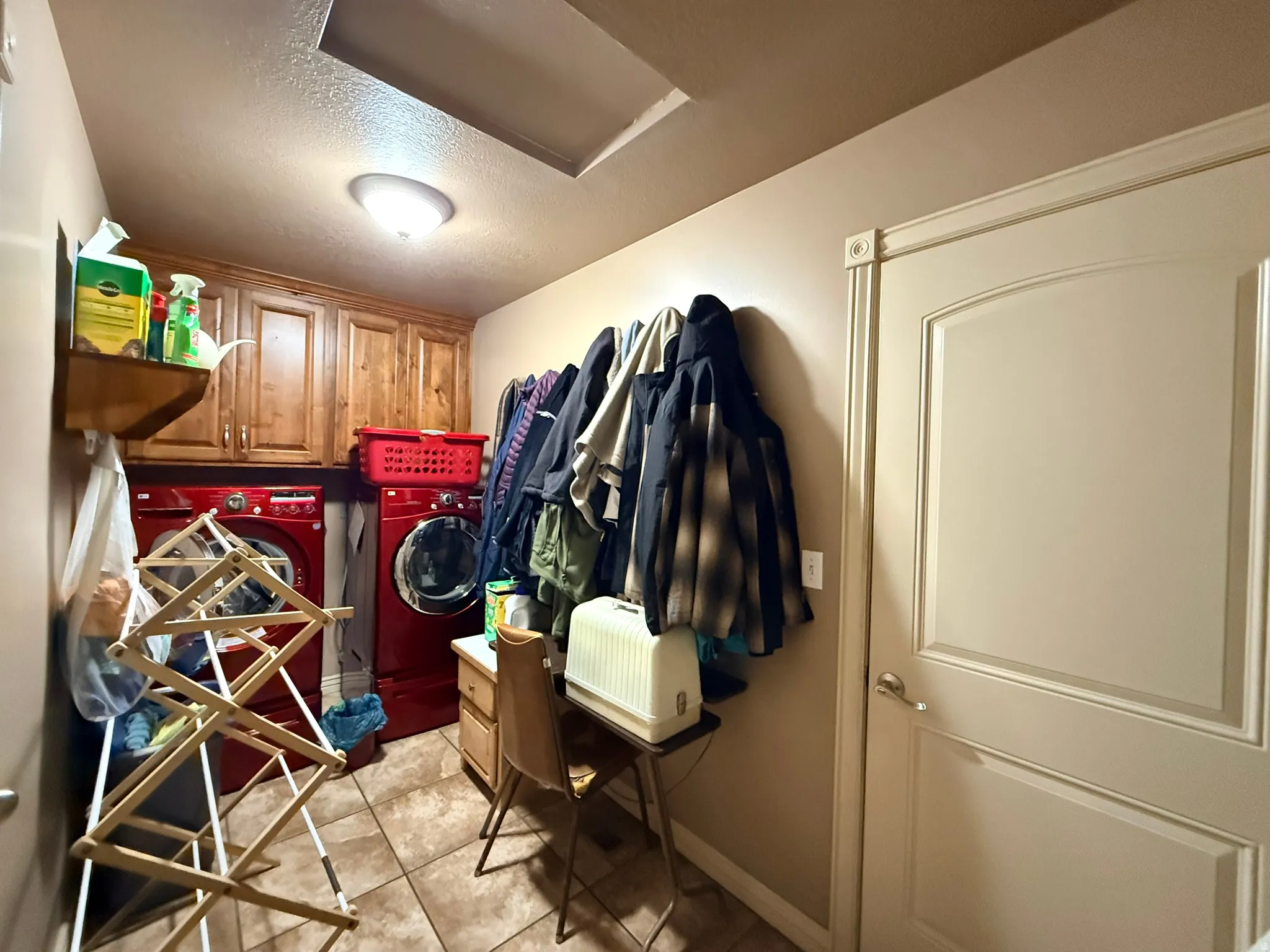 Utility room featuring wood-finish cabinetry, tile flooring, and a flush-mount ceiling light