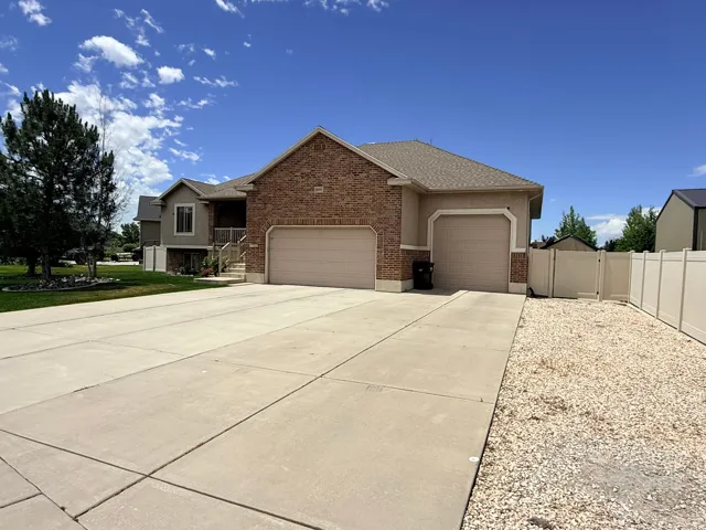 Brick and stucco exterior residence featuring a two-car garage, a single-car garage, and a concrete driveway