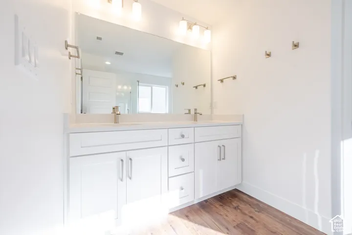White double vanity with shaker-style cabinetry, chrome hardware, dual sinks, and light-toned countertops
