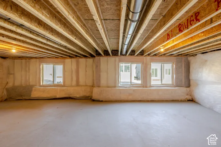 Exposed ceiling joists, three sliding windows, concrete flooring, and insulated walls