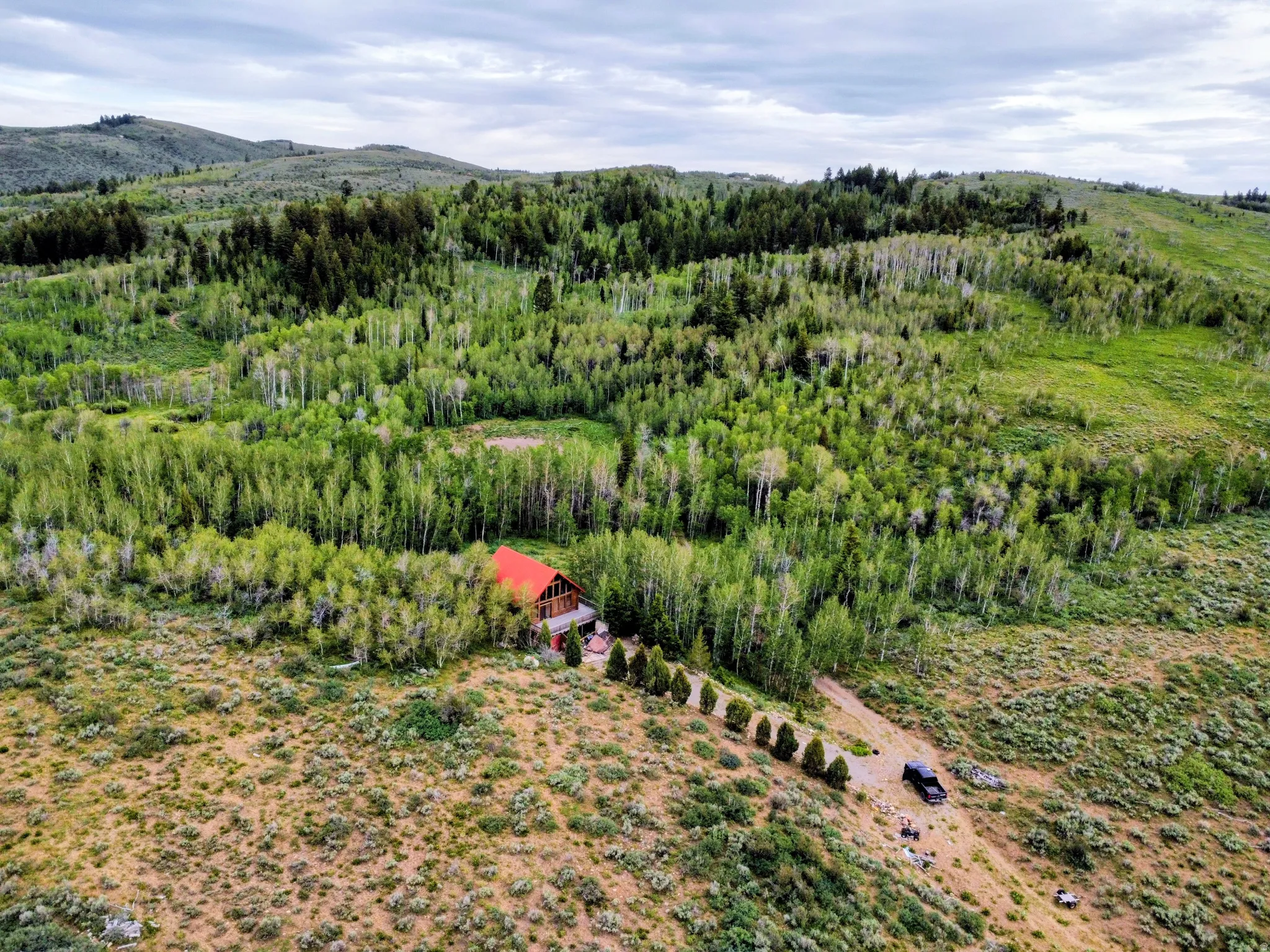 Secluded property featuring a residence with a red roof, surrounded by dense woodlands