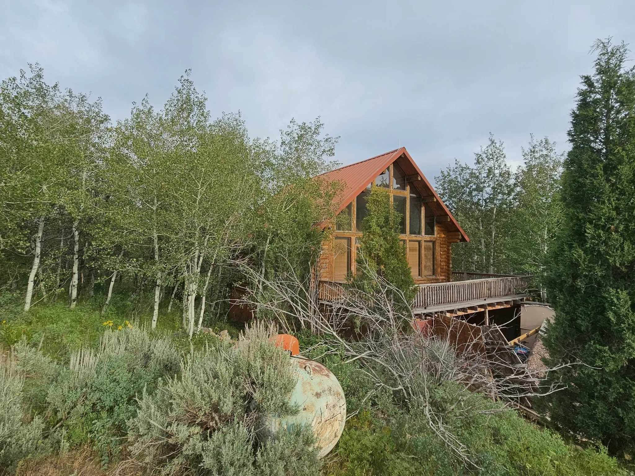 Wood-sided home featuring a prominent A-frame design with a red metal roof