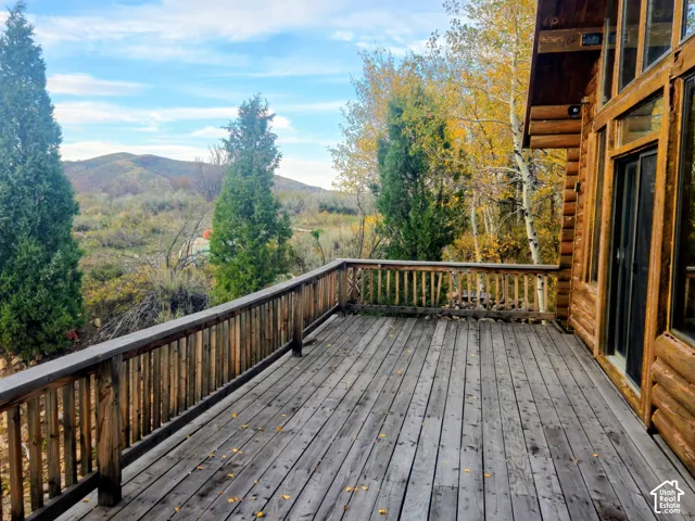 Expansive wood deck with a full wood railing, log home exterior, large windows, and a sliding glass door