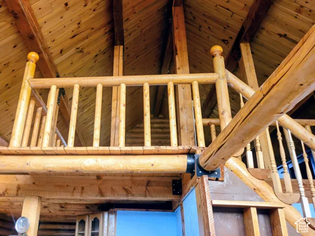 Vaulted wood-plank ceiling with exposed wood beams, log-style balusters, and a wooden newel post