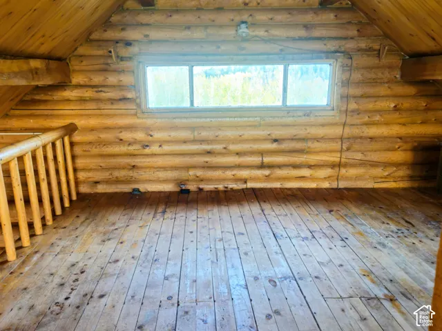Exposed log walls, wood-finish flooring, wood ceiling, and a large window