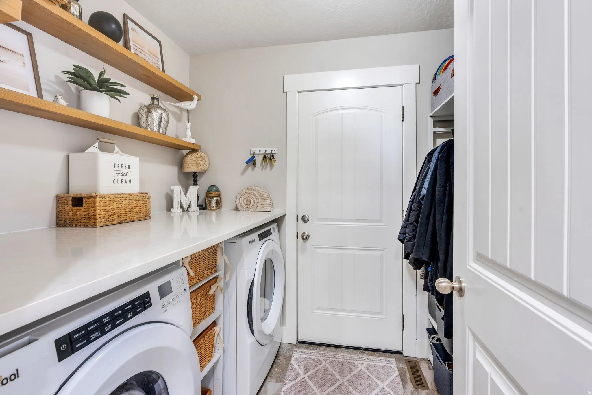 Laundry area featuring white appliances, a light-colored countertop, and light wood-finish shelving