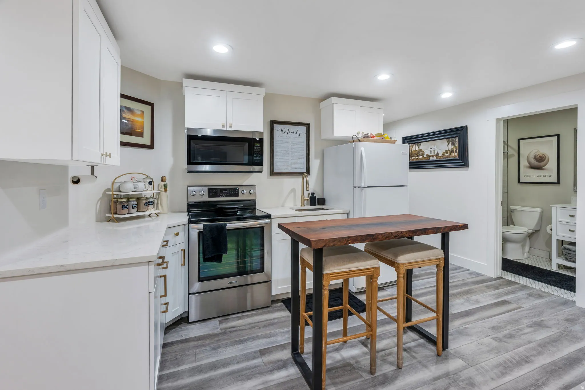 Compact kitchen featuring white cabinetry, light-toned quartz countertops, and stainless steel appliances