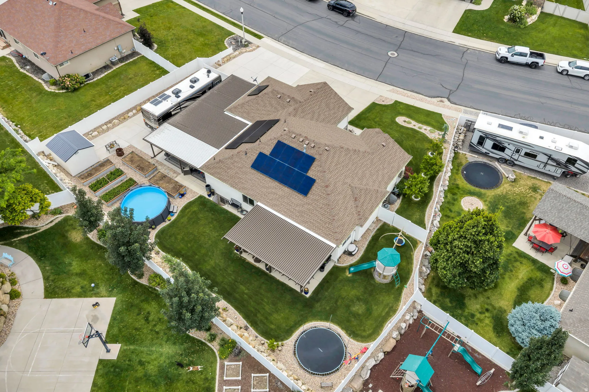 Expansive property featuring a paved driveway, mature landscaping, solar panels, and a covered patio