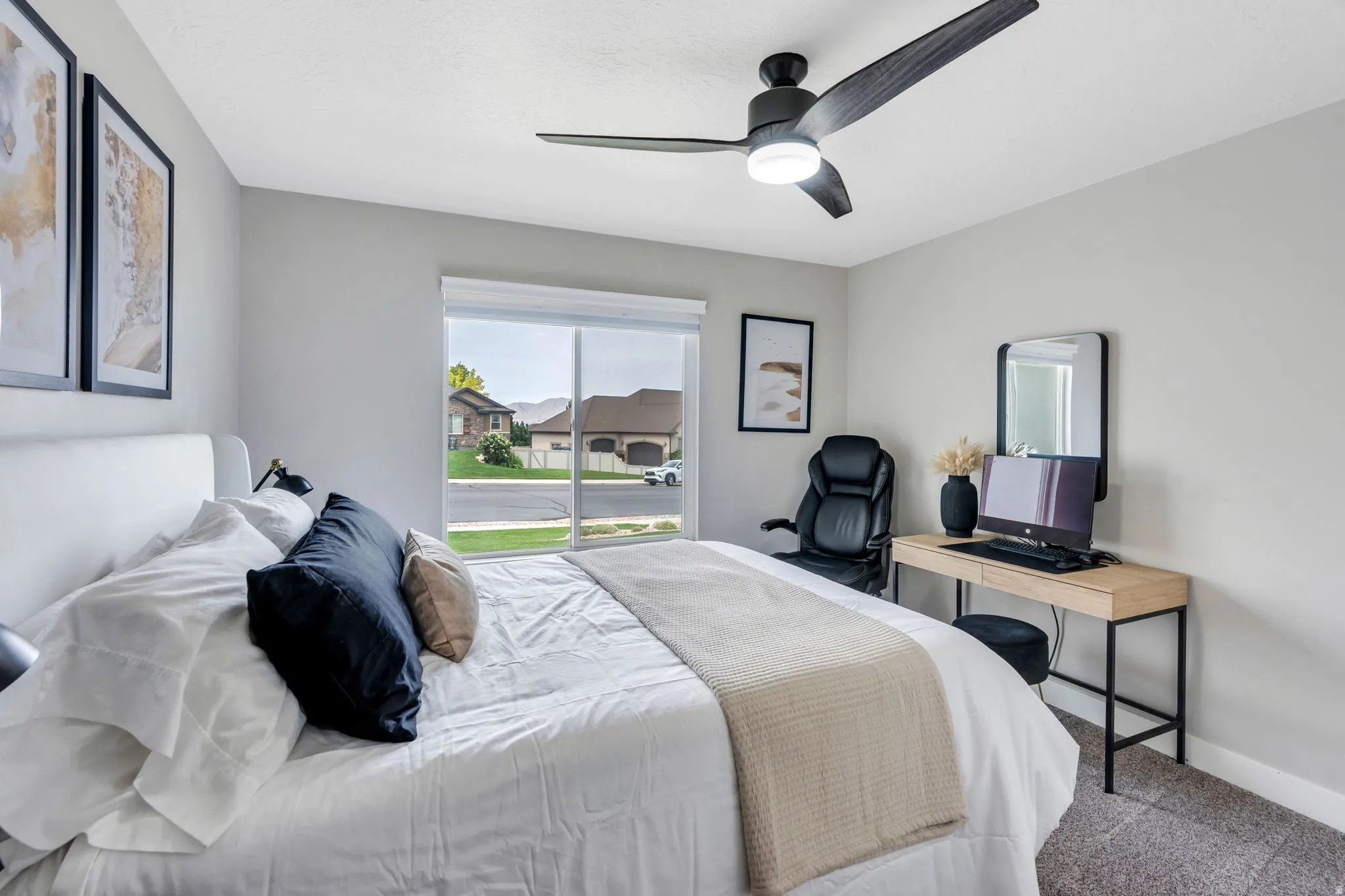 Bright bedroom featuring a large window, a ceiling fan with integrated lighting, and neutral wall paint