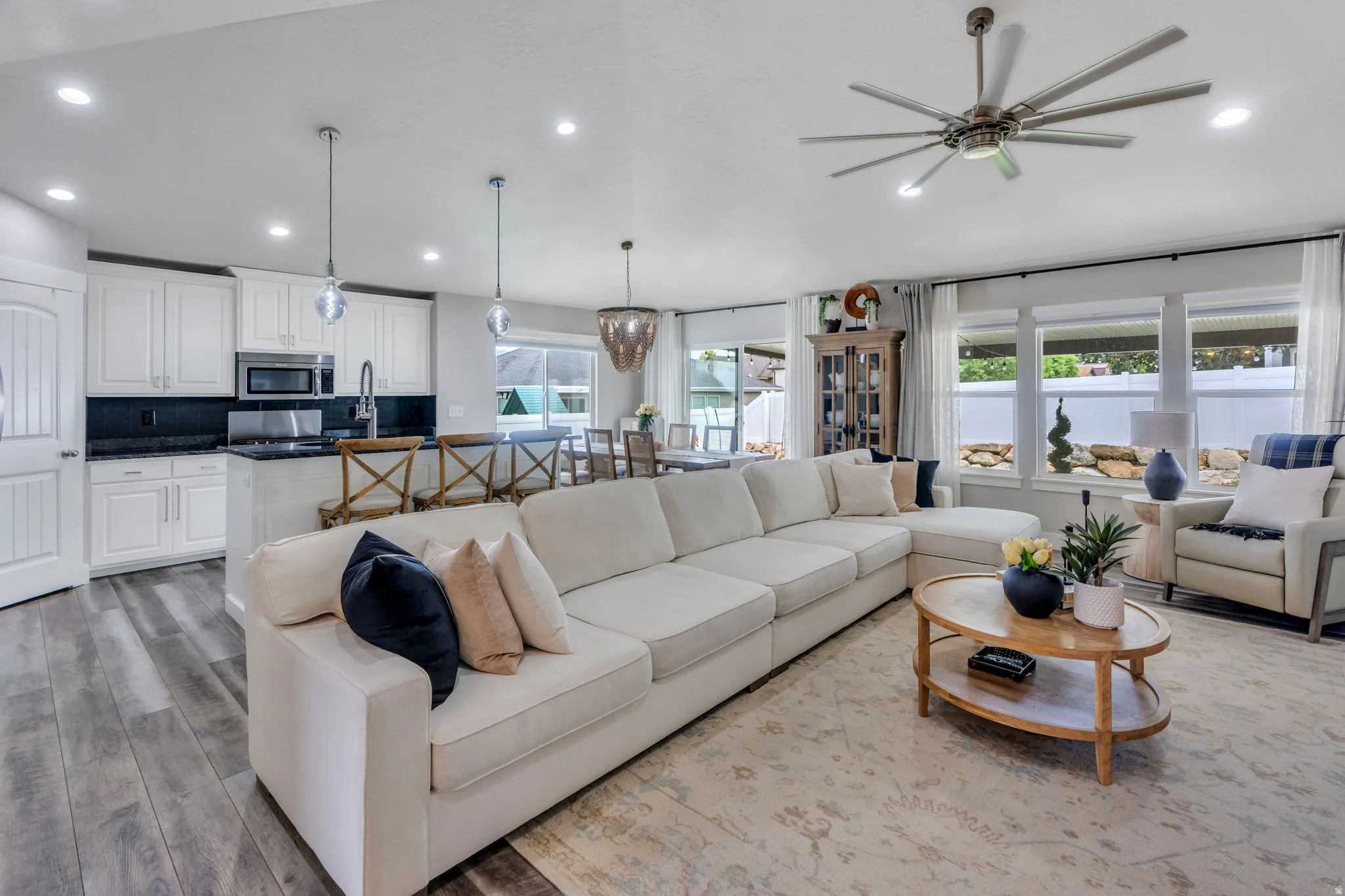 Open-concept living area featuring wood-finish flooring, a contemporary ceiling fan, recessed lighting, and expansive windows