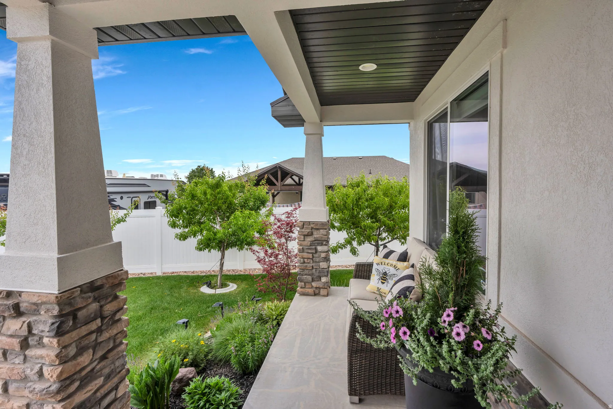 Covered patio with stone-accented pillars and white stucco finish