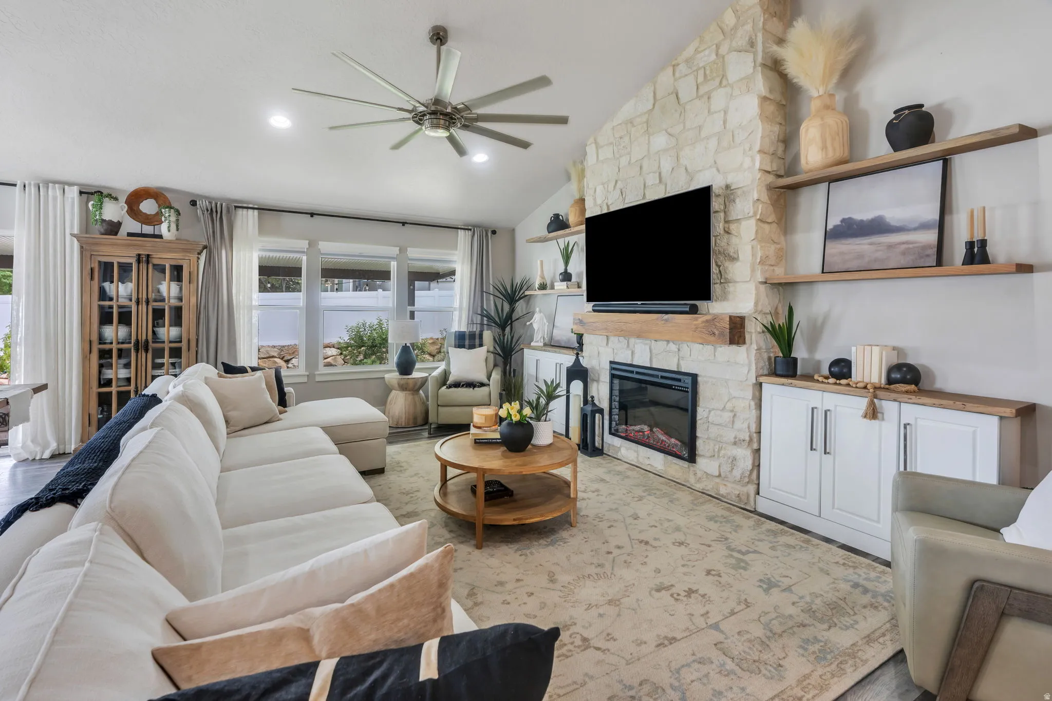 Vaulted ceiling living area featuring a Austin stone-faced fireplace, solid white oak floating shelves and mantel.