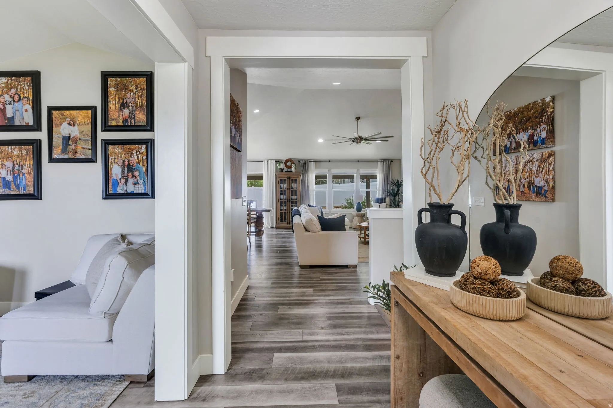 Inviting entryway featuring laminate flooring, vaulted ceilings, white trim, and a wide archway leading to an expansive living space .