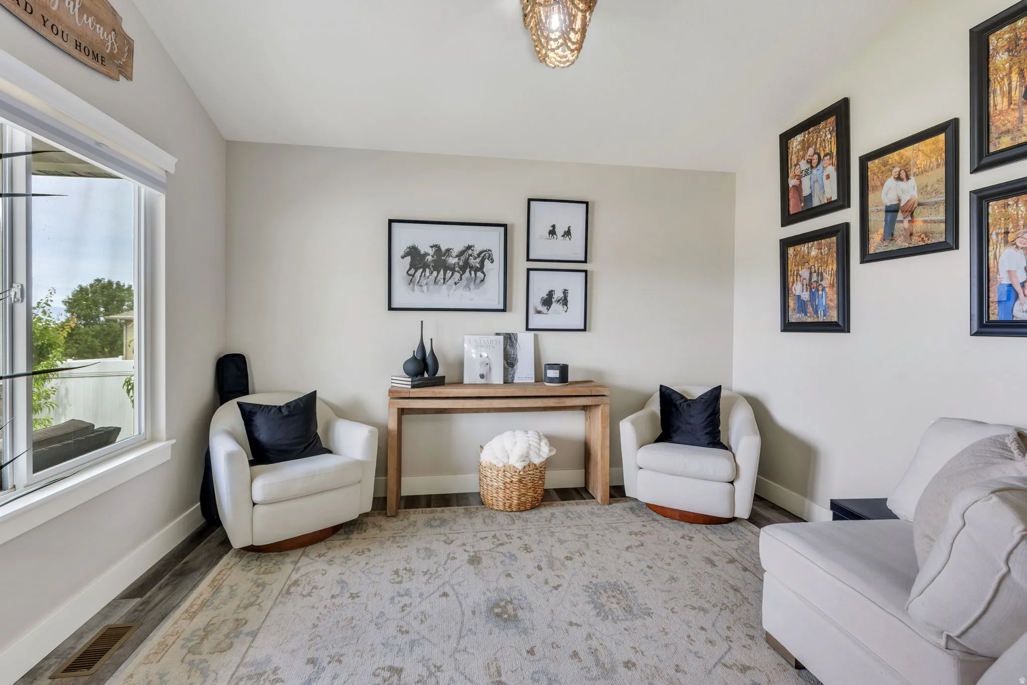 Light-filled room featuring wood-finish flooring, neutral wall tones, and a decorative ceiling light fixture