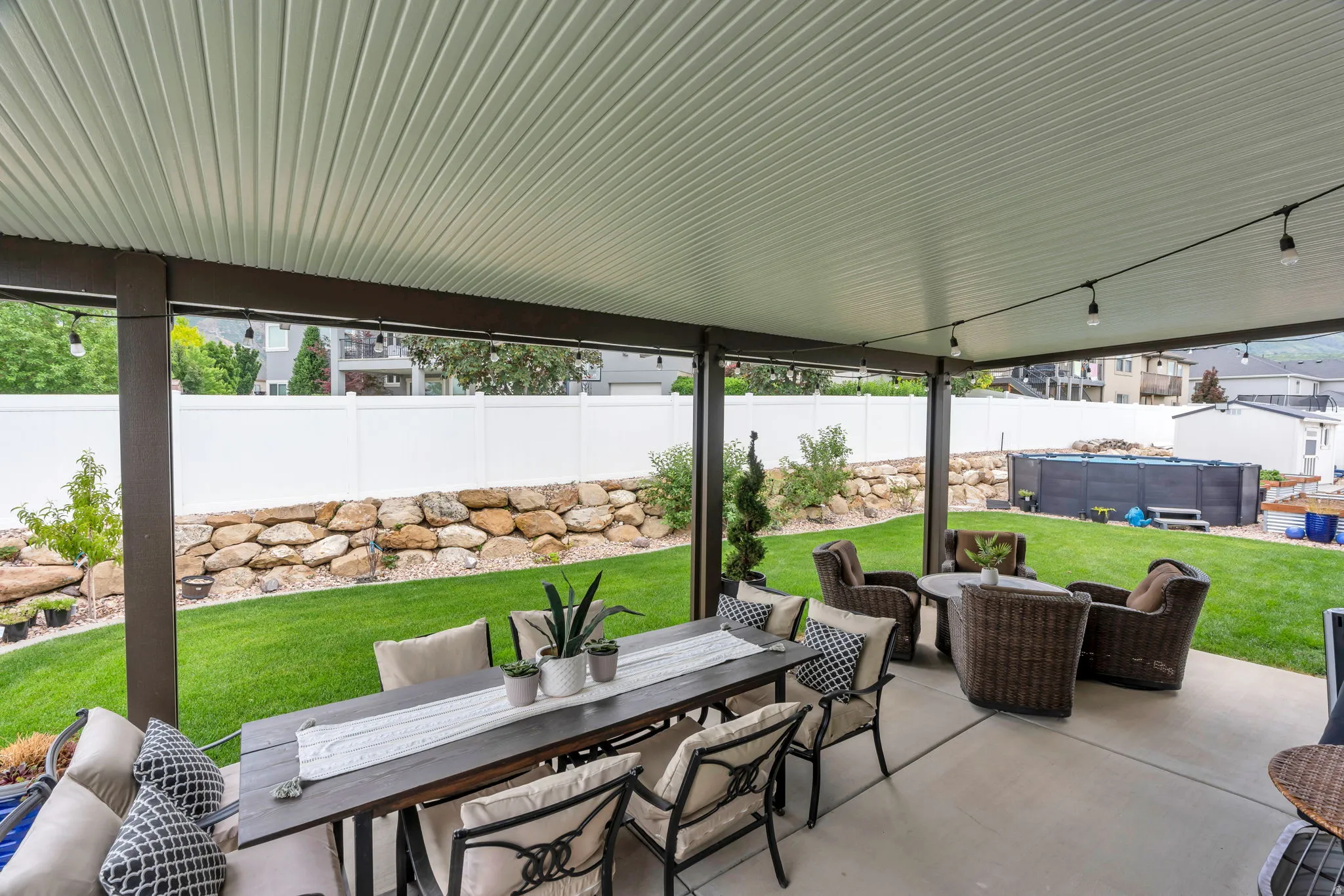 Covered patio with concrete flooring, supported by dark posts