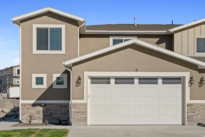 Contemporary stucco exterior featuring a stone accent foundation