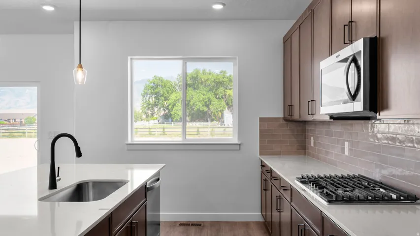 Contemporary kitchen featuring wood-finish cabinetry, light-toned countertops, and a subway tile backsplash