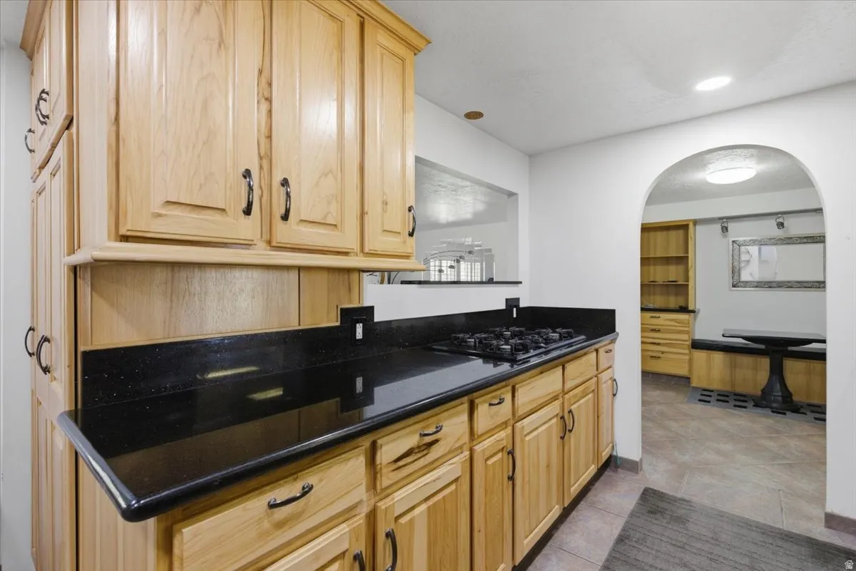 Kitchen featuring natural wood cabinetry, dark countertops, a built-in gas range, and recessed lighting