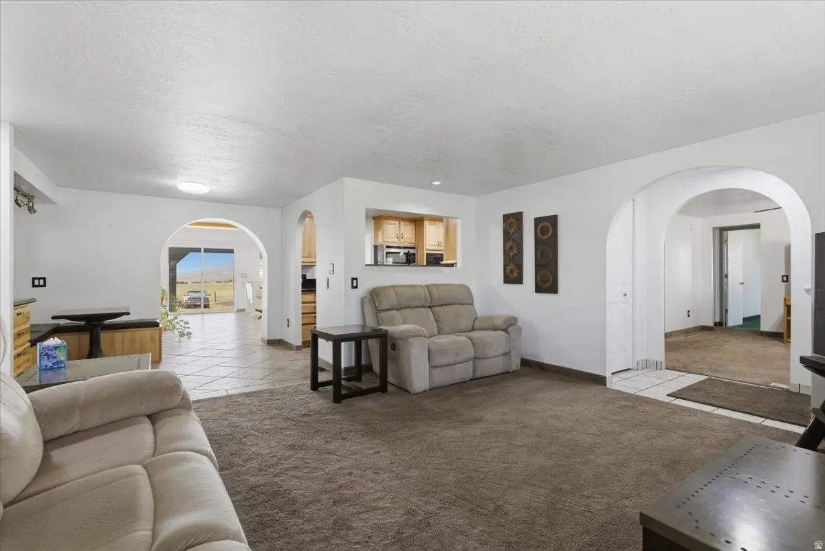 Open concept living area featuring archways and a pass-through window to the kitchen