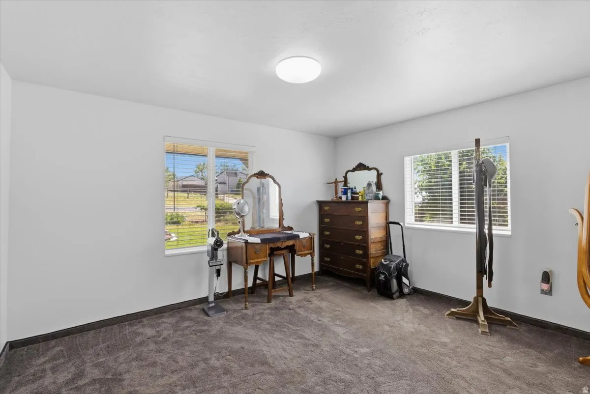 Spacious room featuring neutral white walls and dark carpet flooring