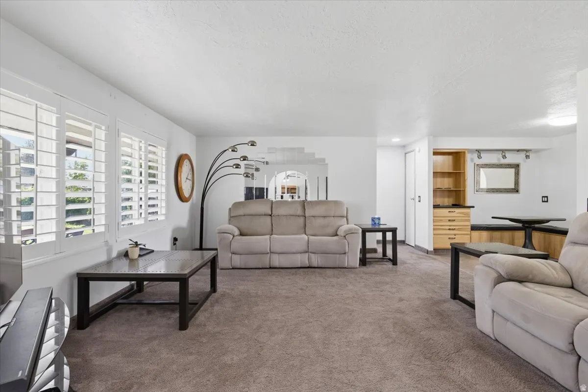 Spacious living area featuring neutral carpet flooring and white walls