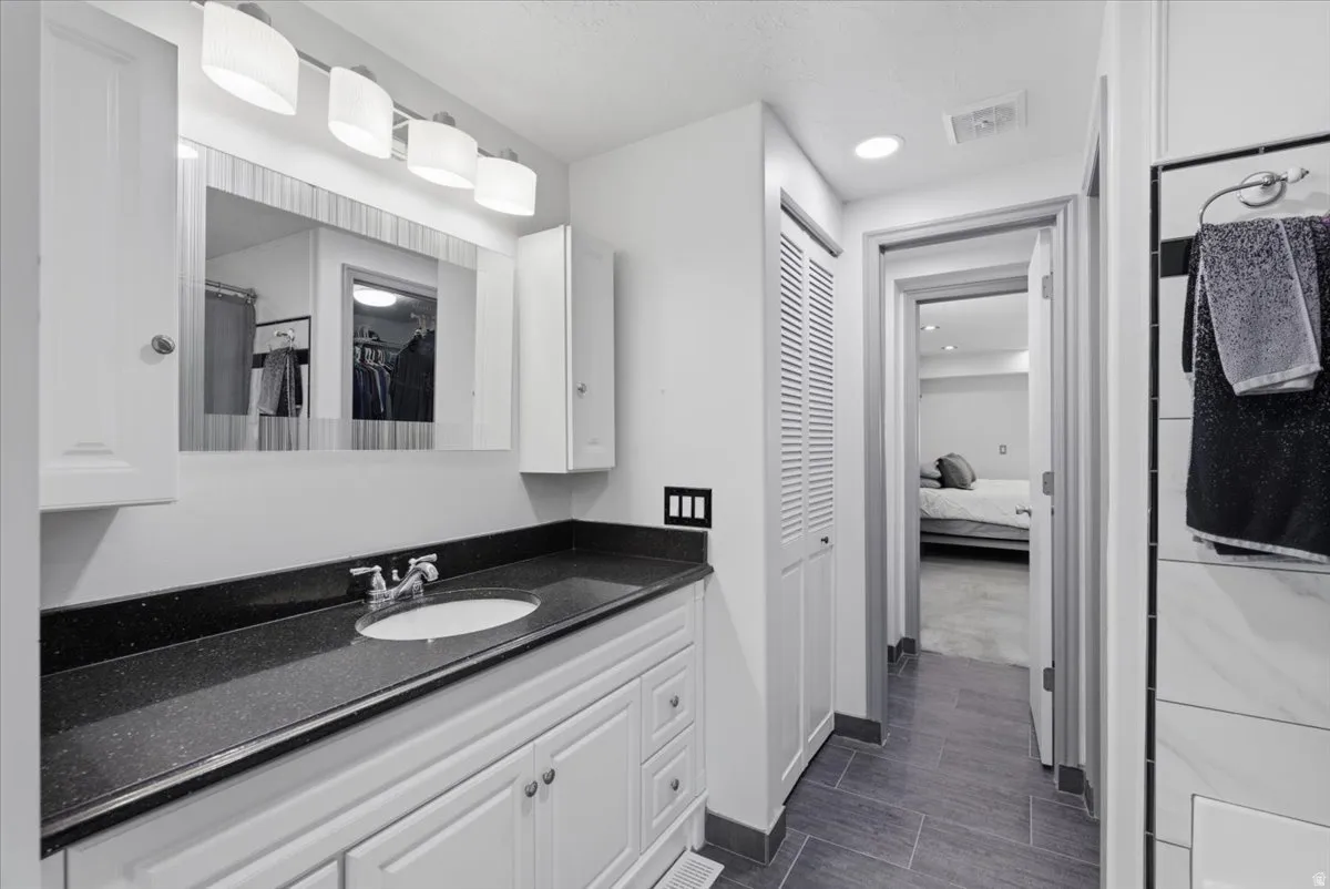 Vanity featuring a dark speckled countertop with an undermount sink and chrome faucet