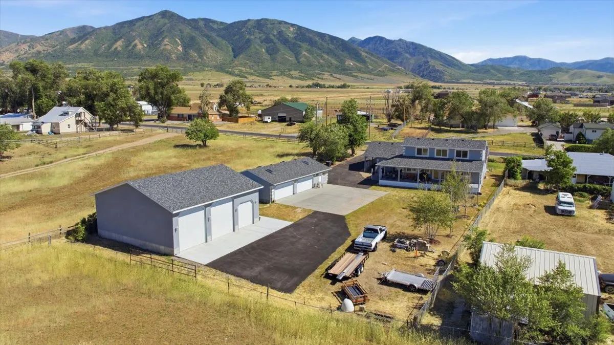 Expansive property featuring a two-story residence with a covered porch, multiple detached garage structures, and a paved driveway