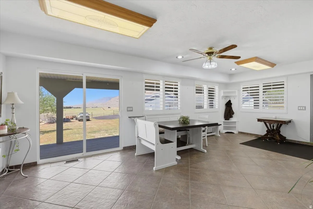 Spacious room with large format tile flooring and multiple windows featuring plantation shutters