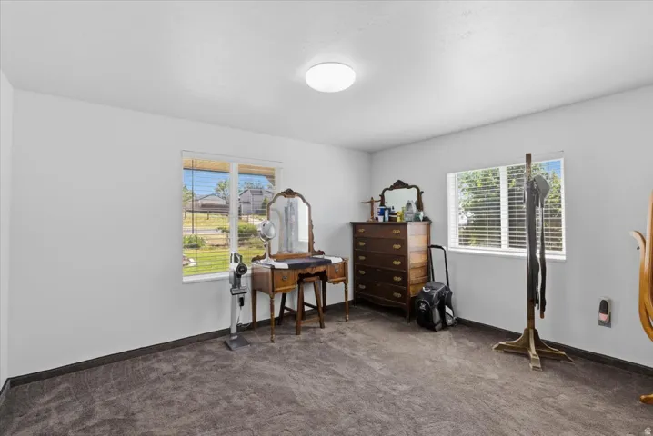 Spacious room featuring neutral white walls and dark carpet flooring
