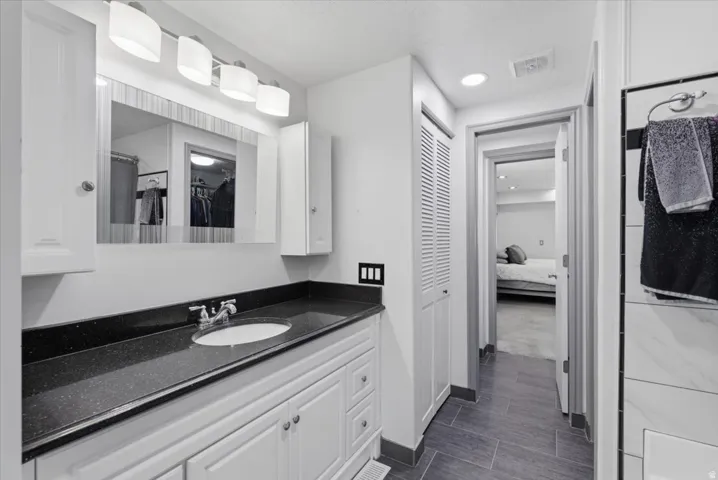 Vanity featuring a dark speckled countertop with an undermount sink and chrome faucet