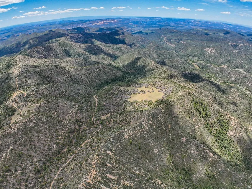 Expansive mountain landscape featuring varied terrain with rolling hills, dense natural vegetation, and scattered clearings