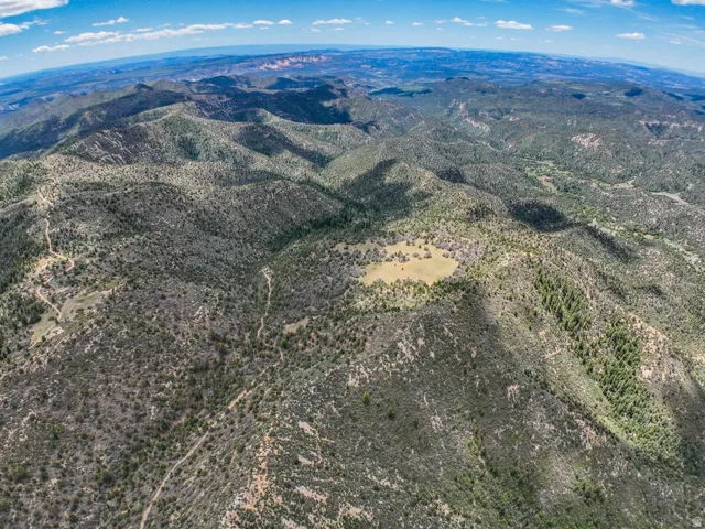 Expansive mountain landscape featuring varied terrain with rolling hills, dense natural vegetation, and scattered clearings