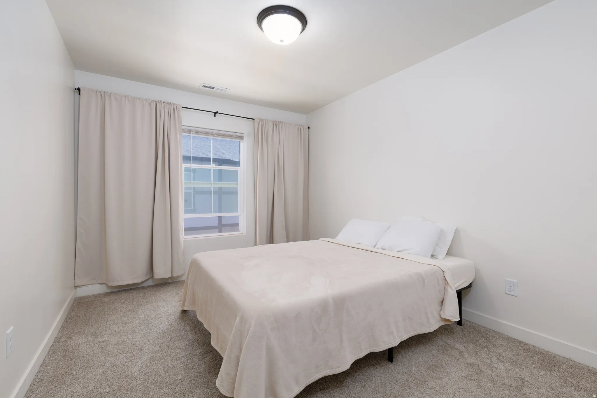 Carpeted room with a double-pane window, flush-mount ceiling light, and white baseboards