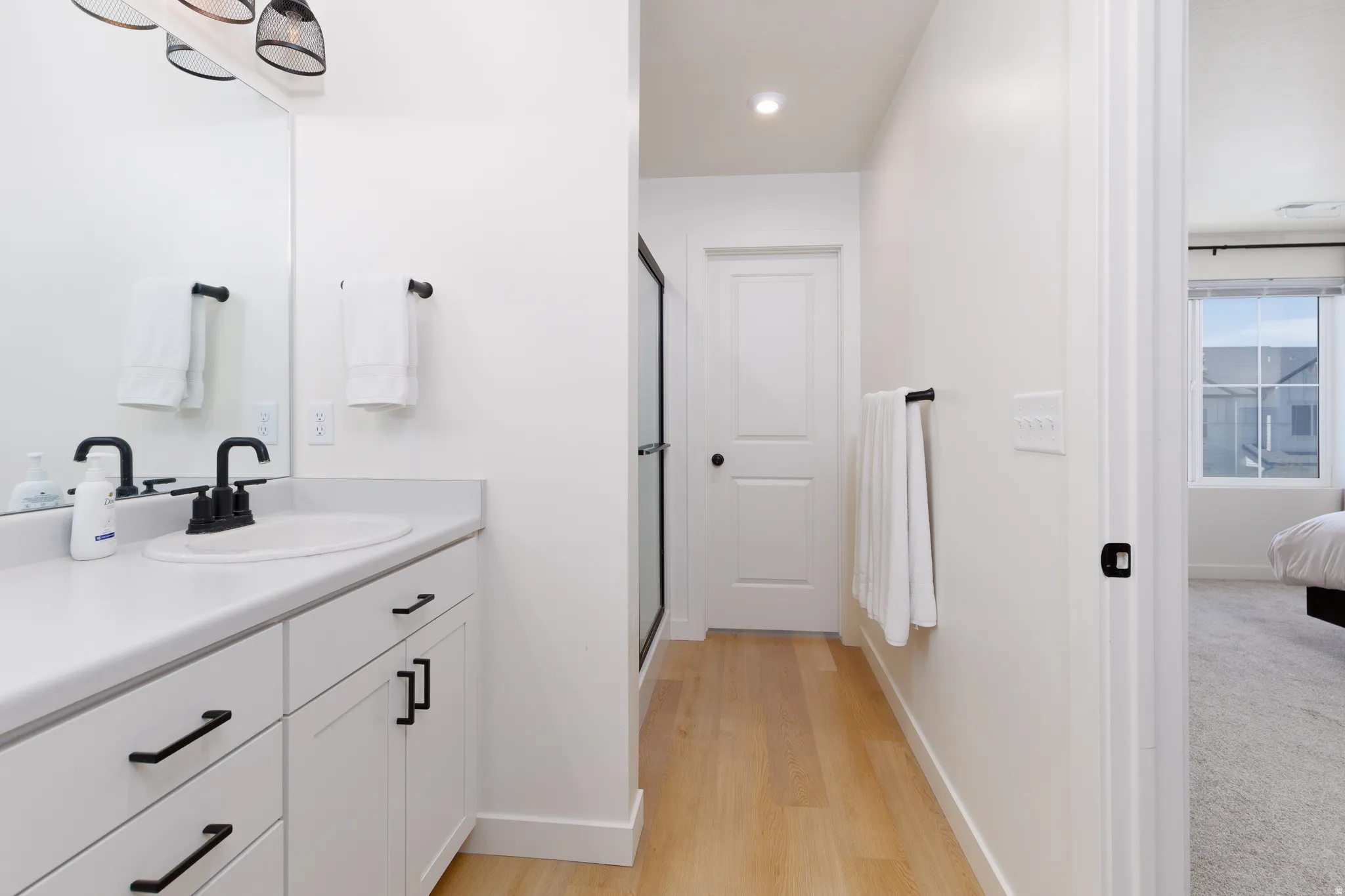 Bathroom vanity with white cabinetry, matte black hardware, and a white countertop
