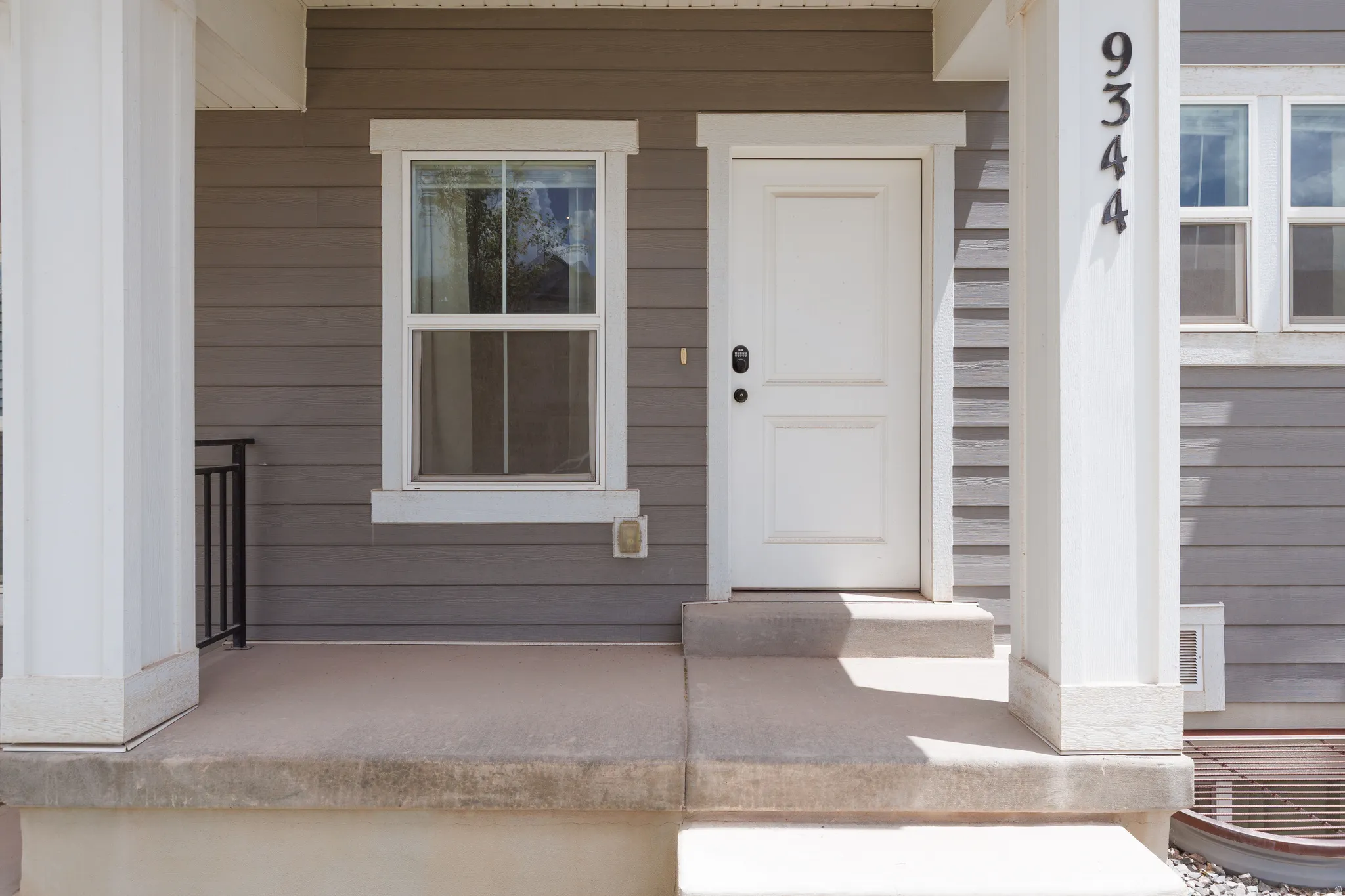 Front entry featuring a white paneled door with black hardware, flanked by a double-hung window with white trim