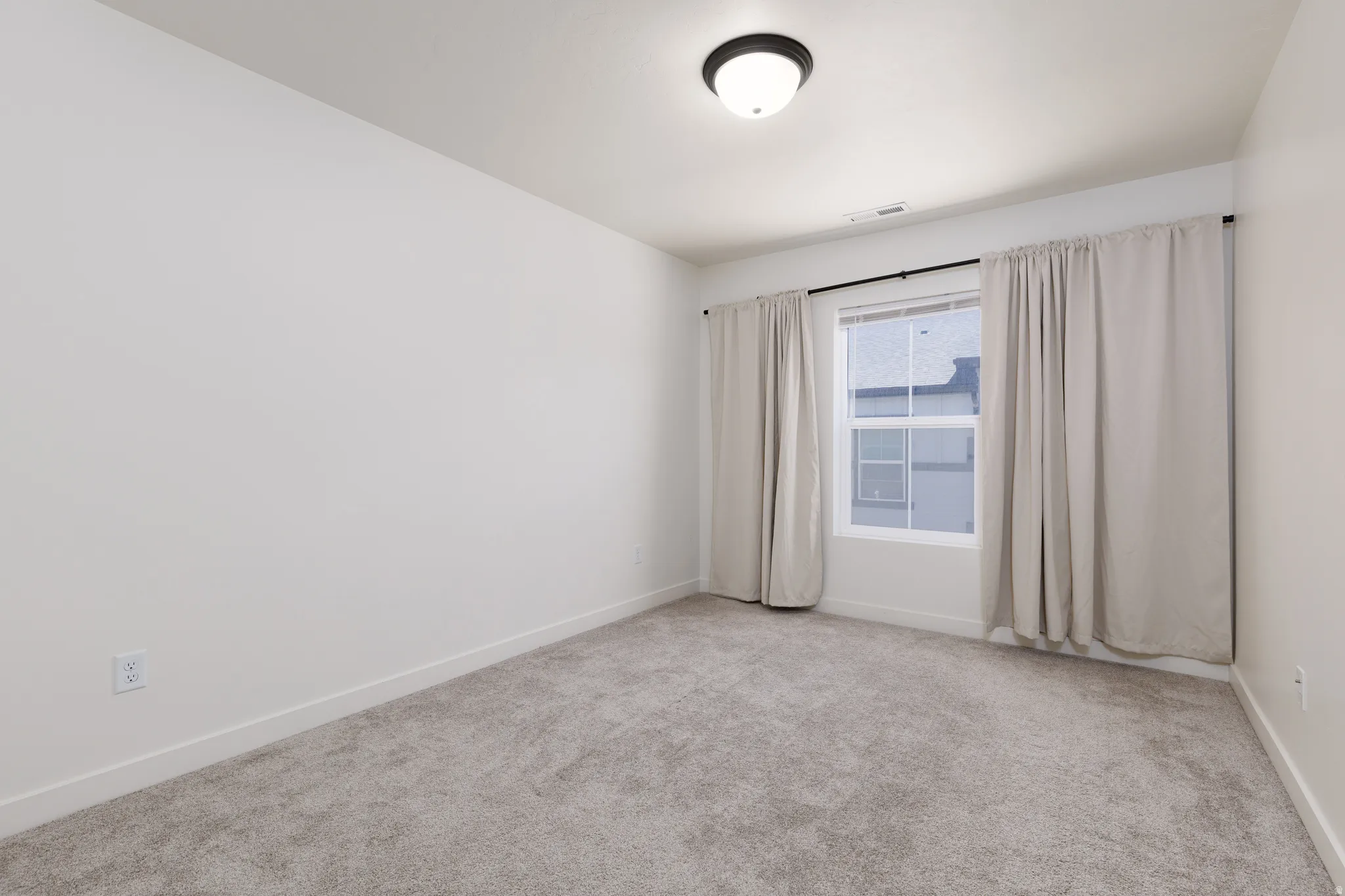 Neutral interior space featuring light gray carpet flooring and white painted walls