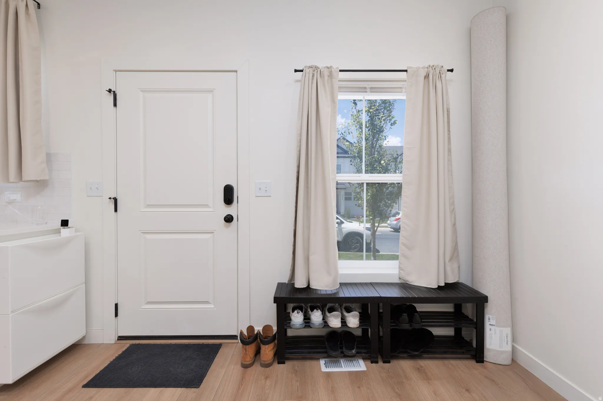 Entryway featuring a white paneled door with black hardware, wood-finish flooring, and a window with natural light