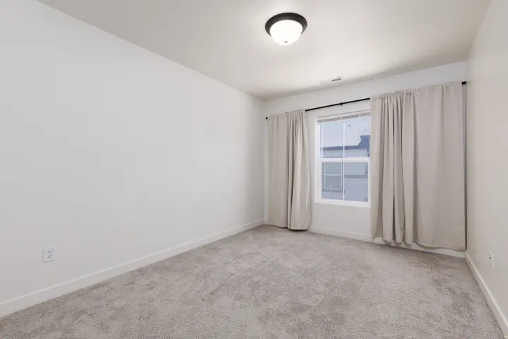 Neutral interior space featuring light gray carpet flooring and white painted walls