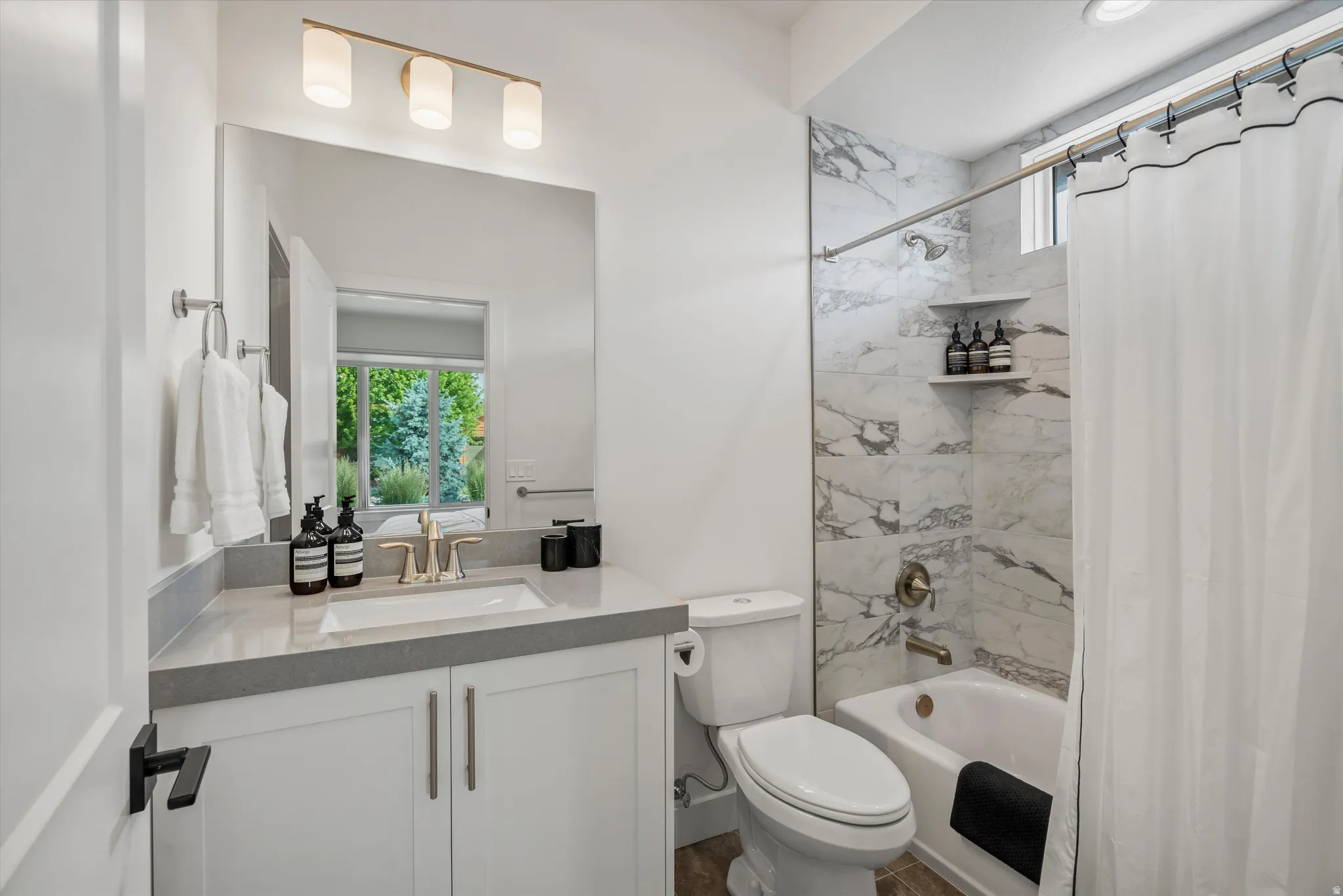 Guest room en-suire bathroom featuring a white vanity with a gray countertop, an undermount sink, and a gold-tone faucet.
