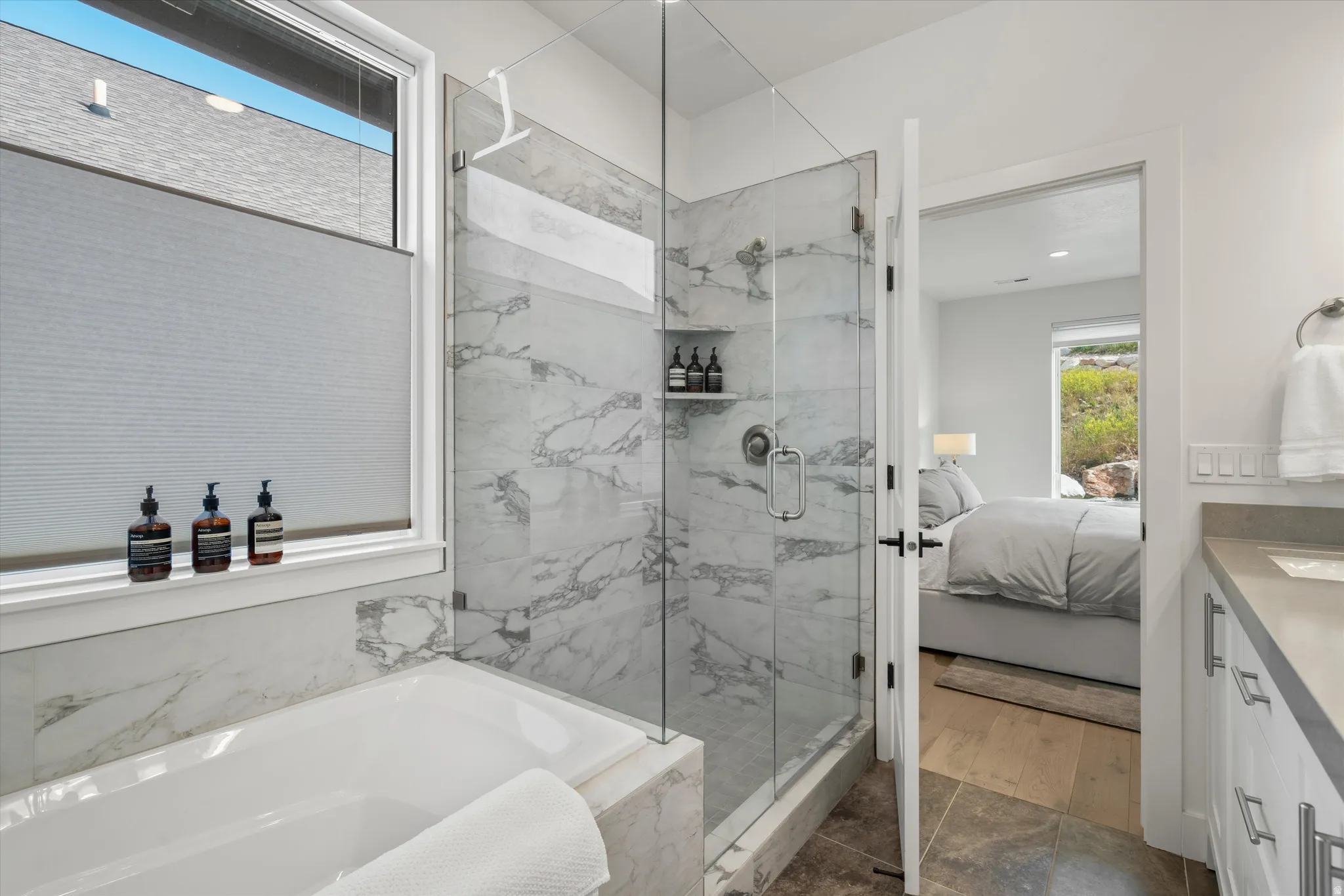 Contemporary bathroom featuring a large soaking tub, glass-enclosed shower with tiled walls, and a window with lots of natural light.
