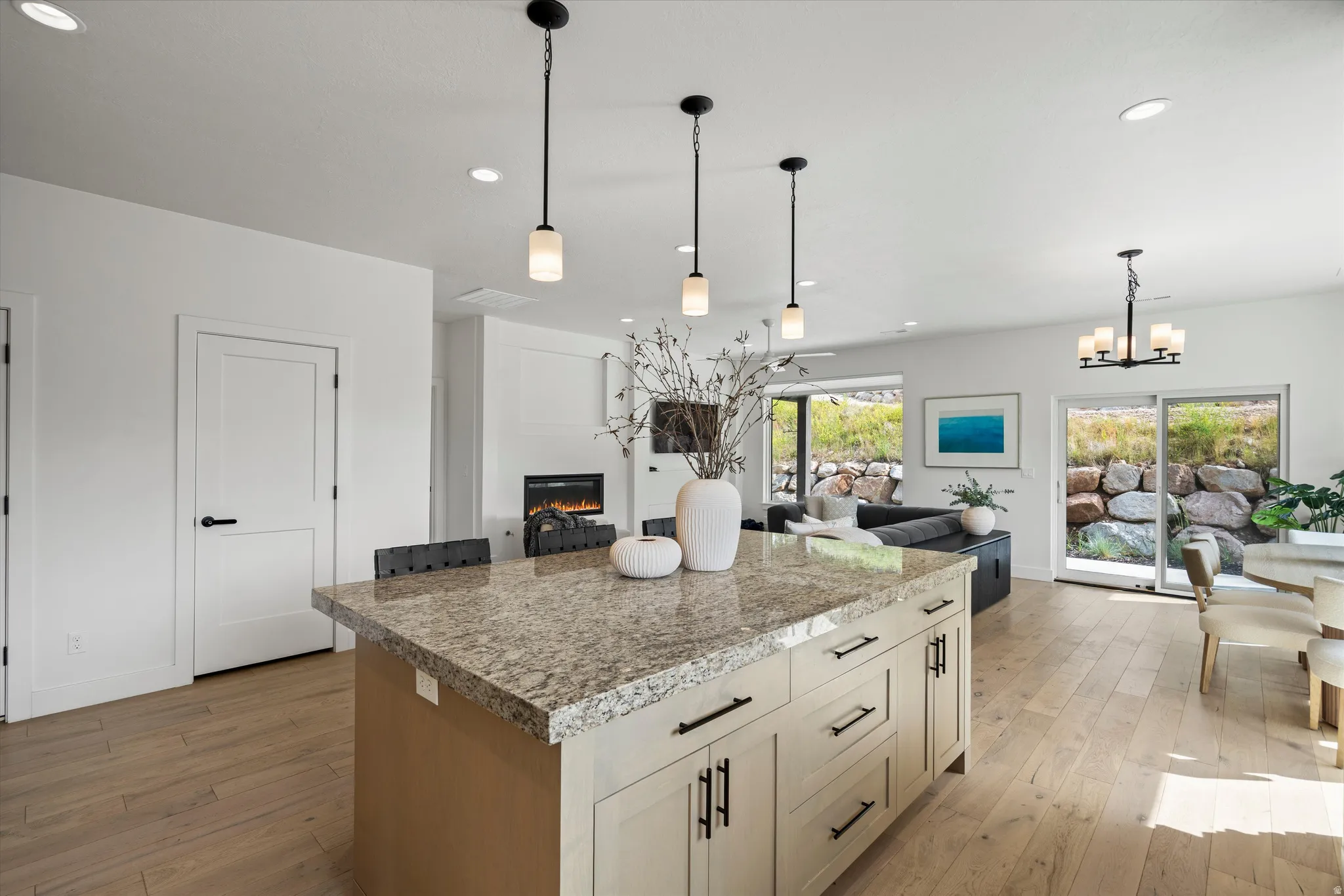 Large kitchen island featuring a light-toned granite countertop and cream-colored cabinetry with dark hardware.