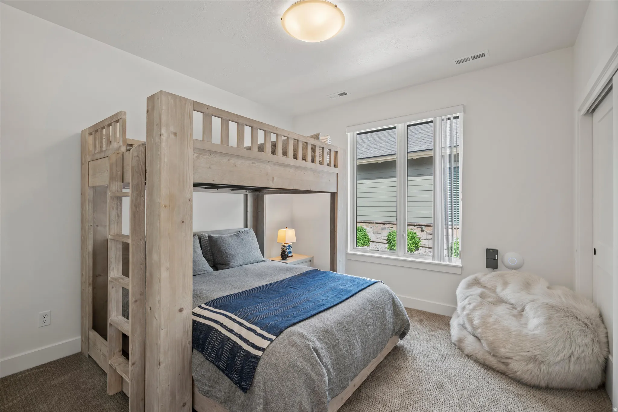 Bedroom featuring high-end bunk bed, white walls, a large window, and carpet flooring