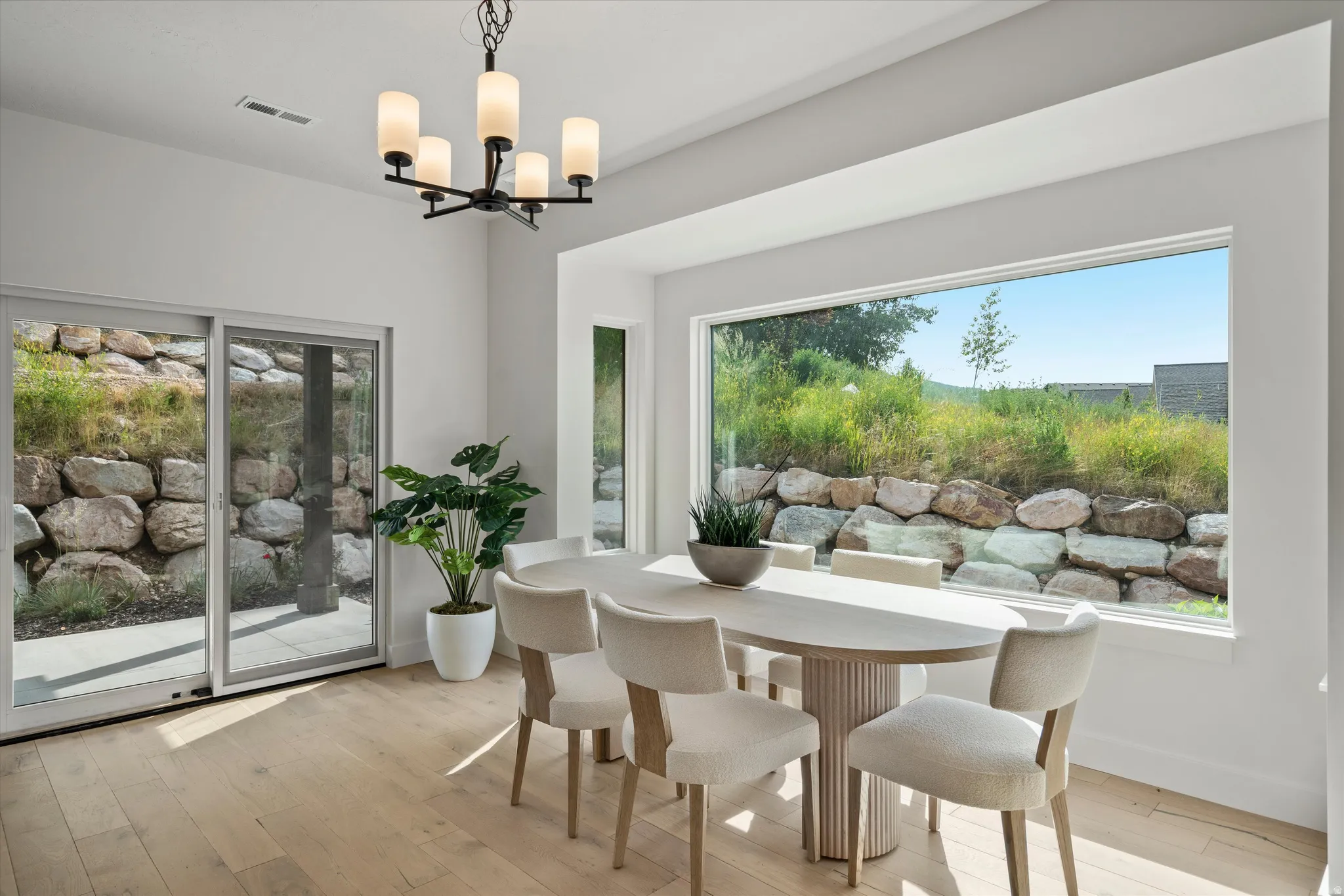 Dining area featuring light wood-finish flooring, a large picture window, and a sliding glass door.