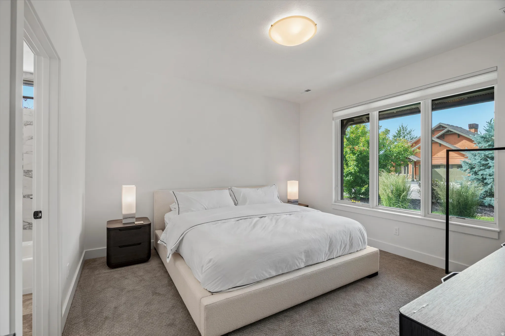 Guest suite featuring plush carpeting, a large three-panel window, and an en-suite bathroom.
