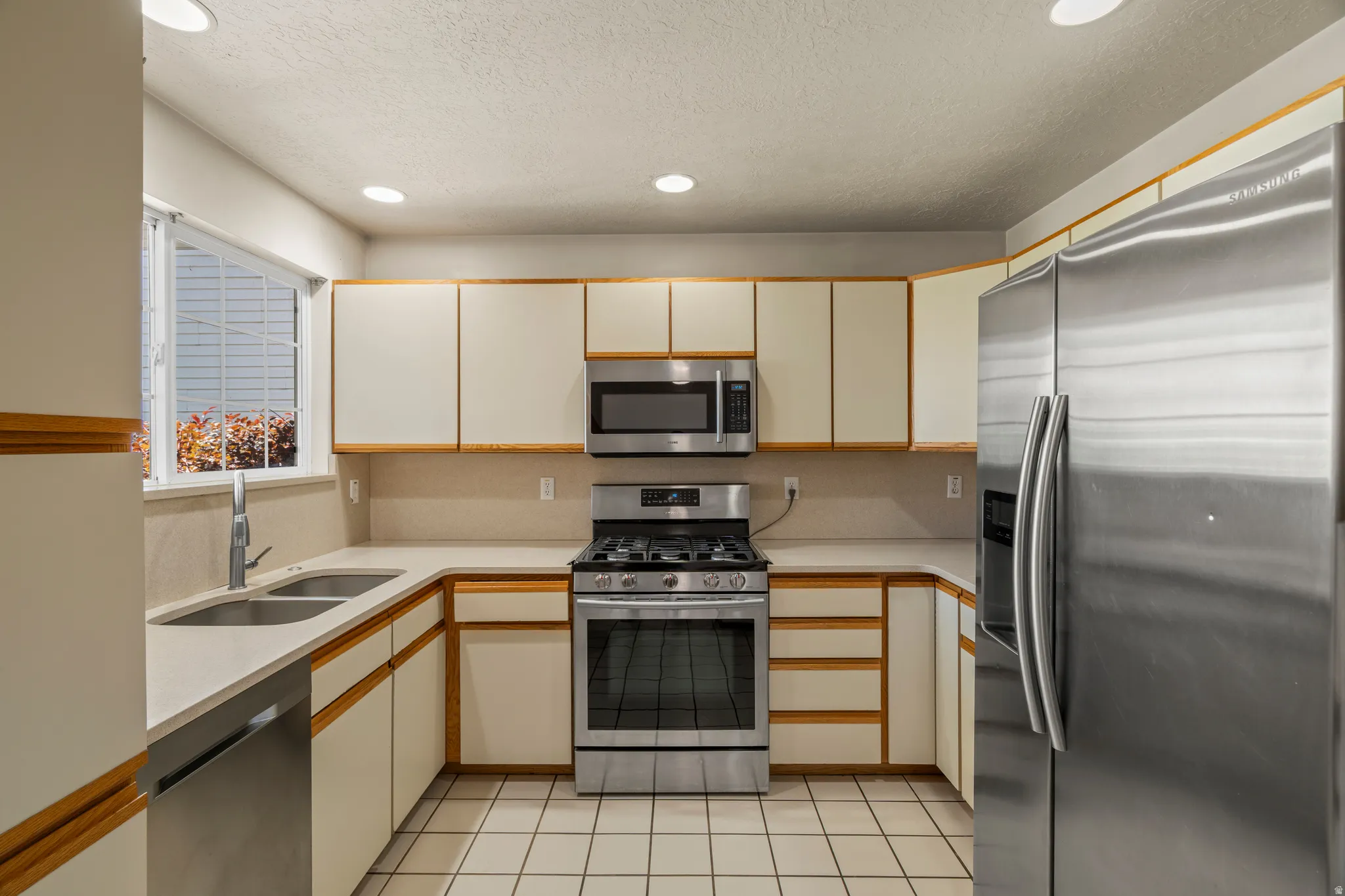 Kitchen featuring stainless steel appliances, light-toned cabinetry, light countertops, and recessed lighting