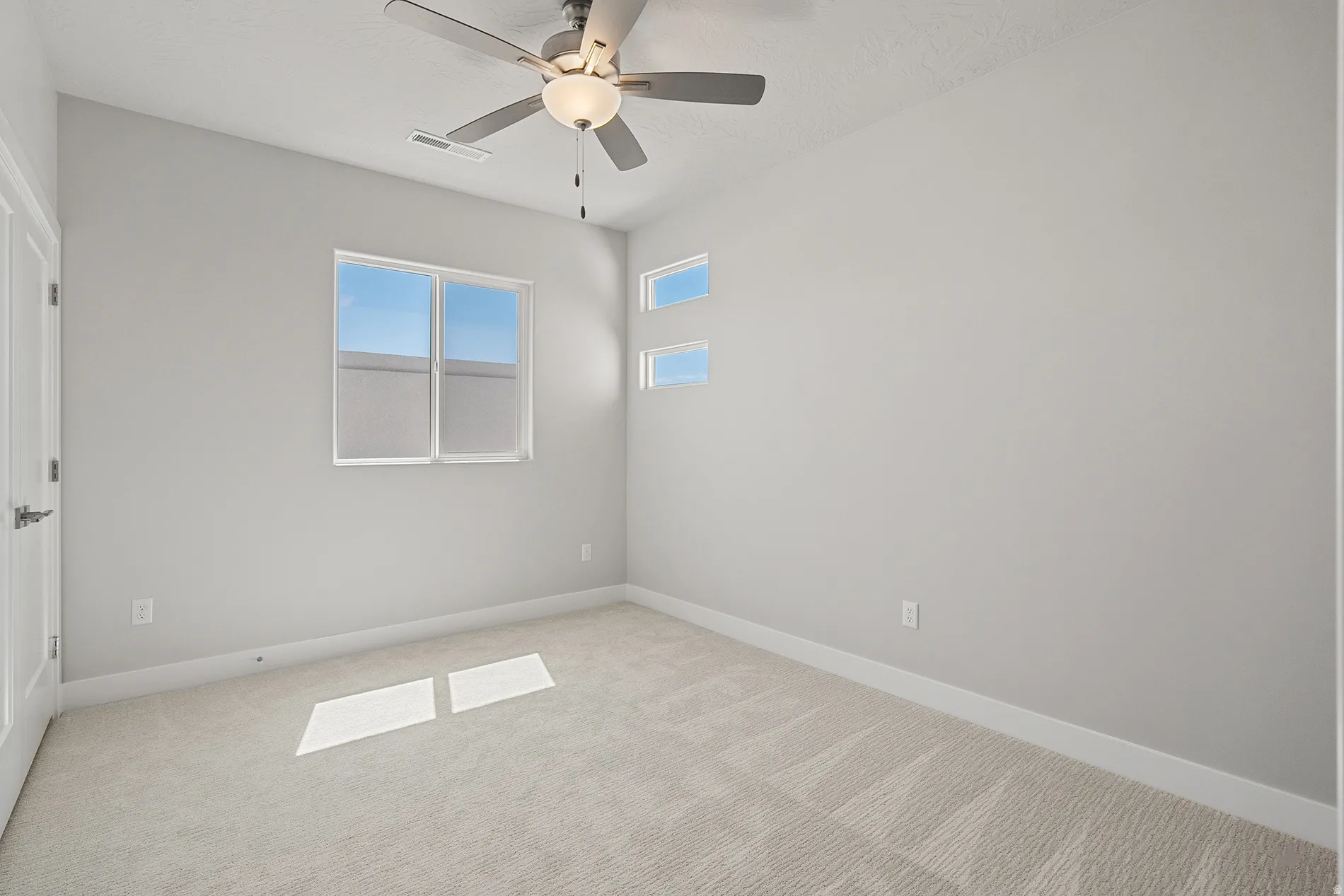 Carpeted interior room featuring a ceiling fan with integrated lighting, a single window, and two upper transom windows