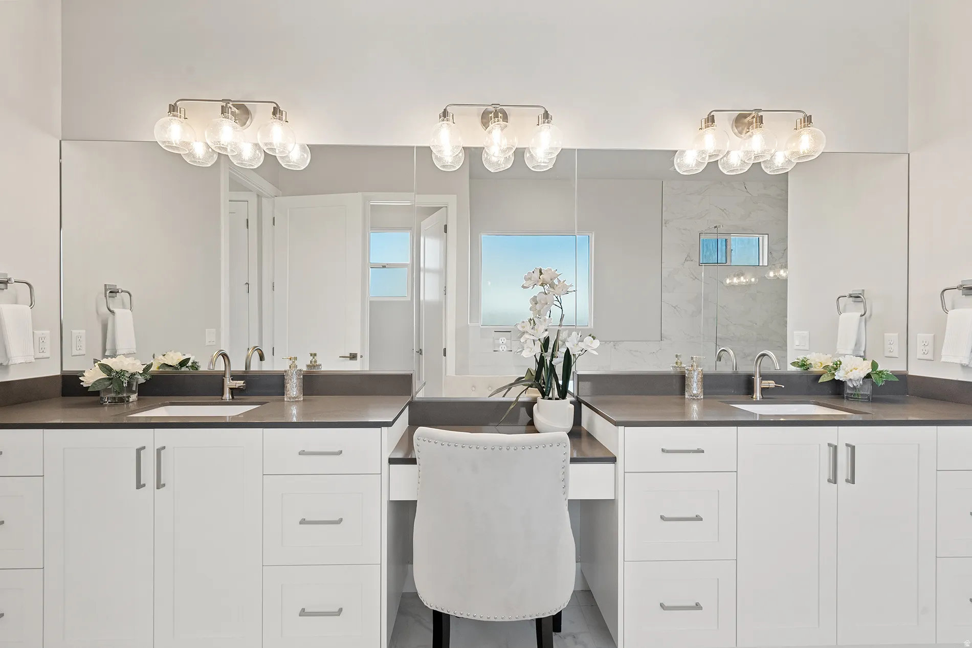 Primary Bathroom Dual vanity featuring white shaker cabinetry, dark countertops, and undermount sinks